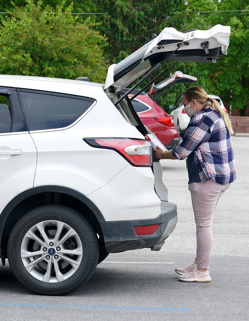 Alyssa Willhite double-checks the requested books with readers through the car trunk